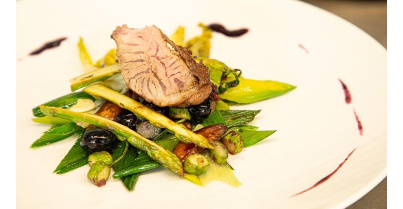 Joues de tête ibérique brièvement poêlées sur poireaux blanchis et asperges vertes sautées aux myrtilles et dattes, accompagnées d'un jus de myrtilles