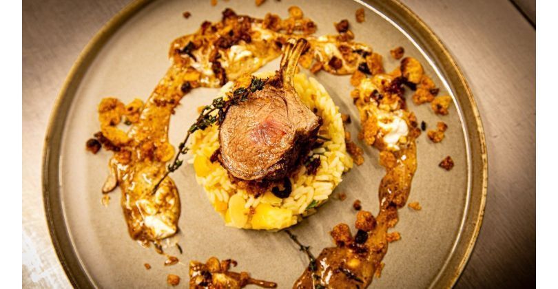 Roasted lamb rack in a breaded cornflake crust with sun-dried tomatoes on orange almond rice