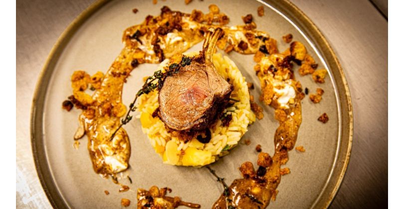 Roasted lamb rack in a breaded cornflake crust with sun-dried tomatoes on orange almond rice