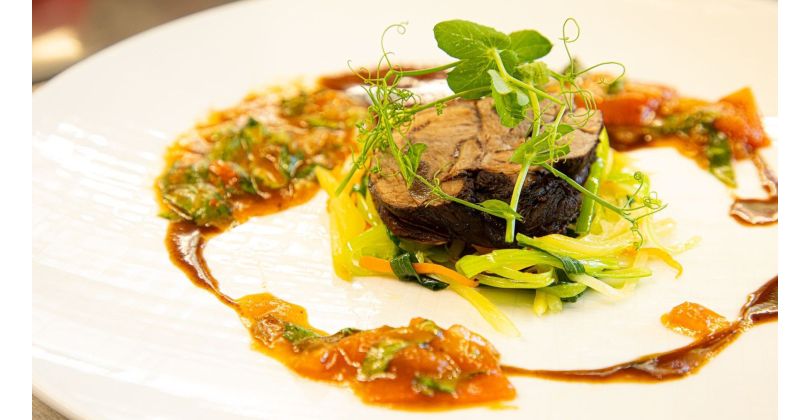 Épaule d'agneau rôtie sur paille de pommes de terre, carottes et poireaux avec jus d'agneau et salsa de tomates et basilic