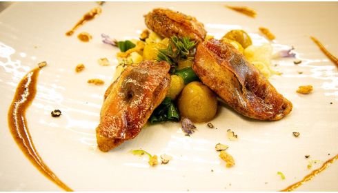 Saltimbocca de poitrine de perdrix rôtie avec fleurons de chou-fleur sautés, oignons nouveaux, ail et pommes de terre nouvelles, servie avec un bouillon de gibier truffé.